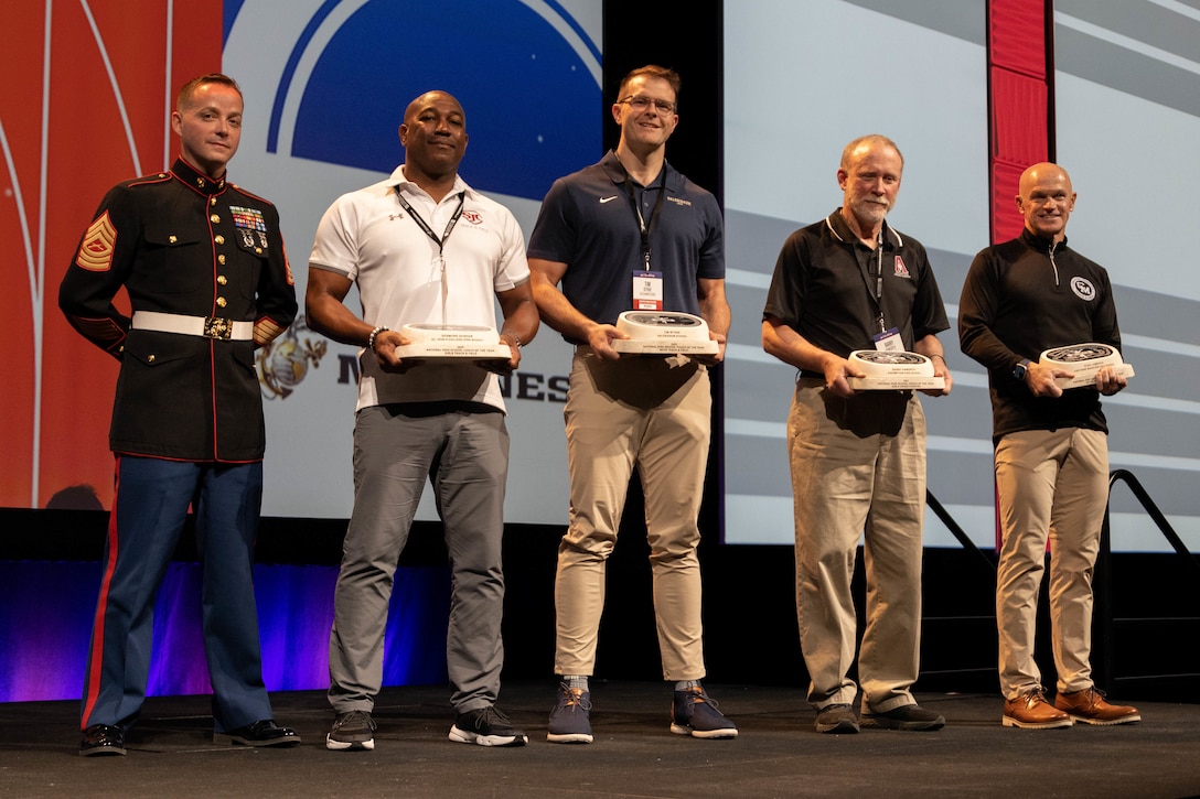 U.S. Marine Corps Michael Wood, an occupational field manager with the Judge Advocate Division, Headquarters, Marine Corps, recognizes the National High School Coaches of the Year Awards at the United States Track & Field and Cross-Country Coaches Association Convention in Aurora, Colo., Dec. 13, 2022. The Marine Corps Recruiting Command is proud to partner with USTFCCCA, during the convention Marines were able to network, participate in professional development sessions with coaches and celebrate the National High School Coaches of the year. (U.S. Marine Corps photo by Lance Cpl. Jennifer Sanchez)