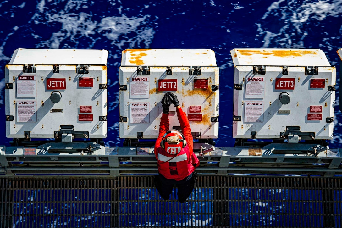 A sailor checks equipment aboard a ship.