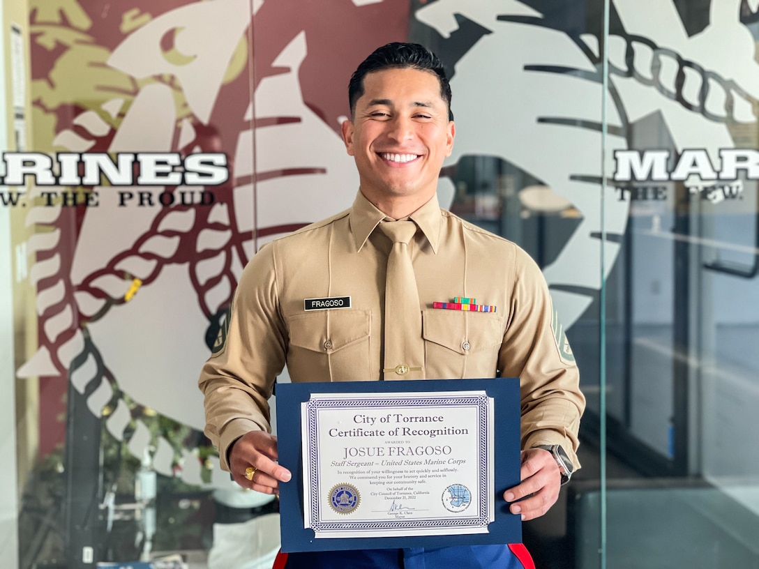 U.S. Marine Corps Staff Sergeant Josue Fragoso, the station commander of Recruiting Sub Station South Bay, Recruiting Station Orange County, 12th Marine Corps District, poses for a photo with a certificate of recognition from Torrance Mayor, George Chen, in Torrance, California on Dec. 22, 2022. SSgt. Fragoso responded to a robbery in progress on Dec. 20, 2022, outside his office at Daniel's Jewelers and helped apprehend two suspects. (U.S. Marine Corps photo by SSgt. Immanuel Johnson)