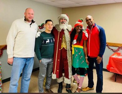 Todd Bishop, center, and Tiwana Sears, center right, pose for a photo with current and former team members during a U.S. Army Medical Materiel Agency holiday party.