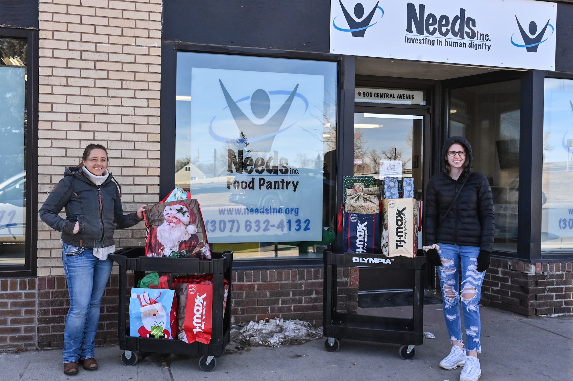 Sara Cook, 90 CONS agency/organization program coordinator, and Senior Airman Kyra Blystone, 90 CONS contracting officer, pose with the presents they are dropping off for local families in need as part of Needs Inc Adopt a Family Program in Cheyenne, Wyoming, Dec 19, 2022. 90 CONS came together for the second year in a row to support two families in need, so they did not have to choose between giving their kids food or celebrating the holiday season. (U.S. Air Force photo by Joseph Coslett Jr.)