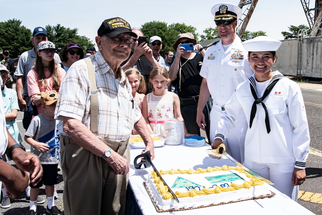 Naval Support Activity, Lakehurst, centennial attendees cut a cake at Joint Base McGuire-Dix-Lakehurst, N.J., June 25, 2021. The ceremony took place at Hangar No. 1, the first major facility built at Lakehurst and previously housed helium-filled dirigibles. Today, the hangar is home to the Center for Naval Aviation Technical Training and improves sailor’s general knowledge of launching aircraft.  (U.S. Air Force photo by Airman 1st Class Azaria E. Foster)