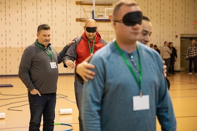 Matt Palmisano, the new integrative prevention officer for the Illinois National Guard, helps guide his teammate during a resiliency exercise Dec. 1 on Camp Lincoln in Springfield, Ill. During the exercise Illinois National Guard servicemembers were put in teams and asked to help guide each other through obstacles while blindfolded. The exercise assisted groups with building trust while working together in a team environment. Instructors from NATAL, the Israel Trauma and Resiliency Center, brought resiliency training to the Illinois National Guard as a U.S. pilot course called Operational Stress Management and Resiliency Care for First Responders. The course ran from Nov. 29 to Dec. 2 at Camp Lincoln, Springfield, followed by another week of teleconference training.