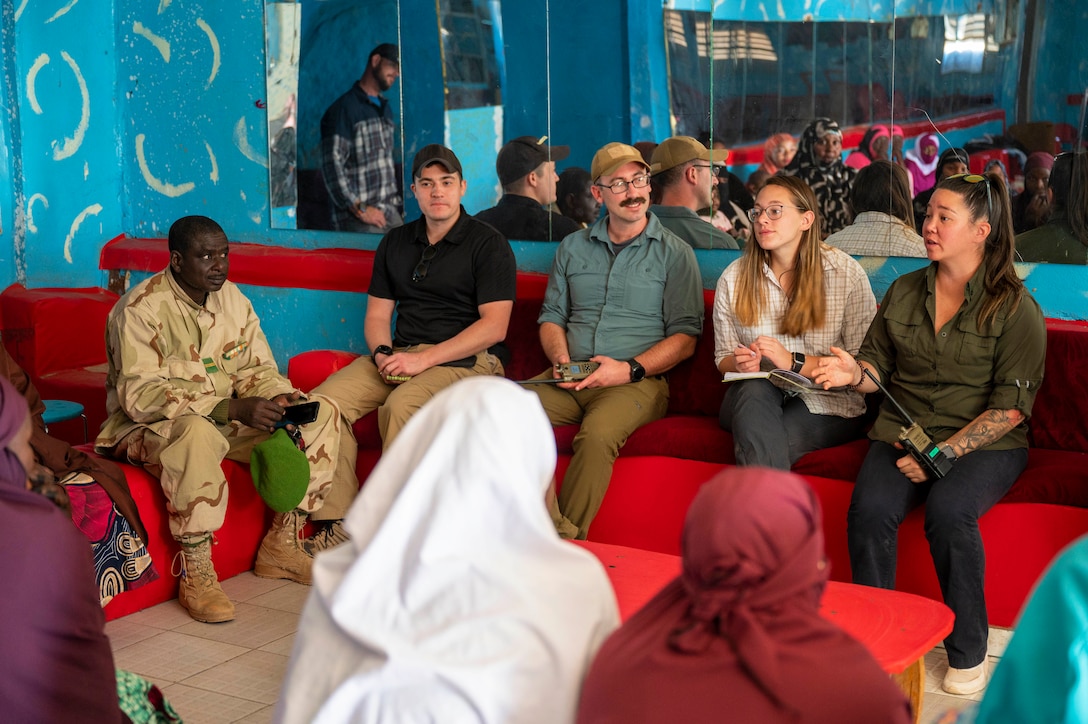 Several U.S. service members in civilian clothing talk with a group of Nigerien military spouses.