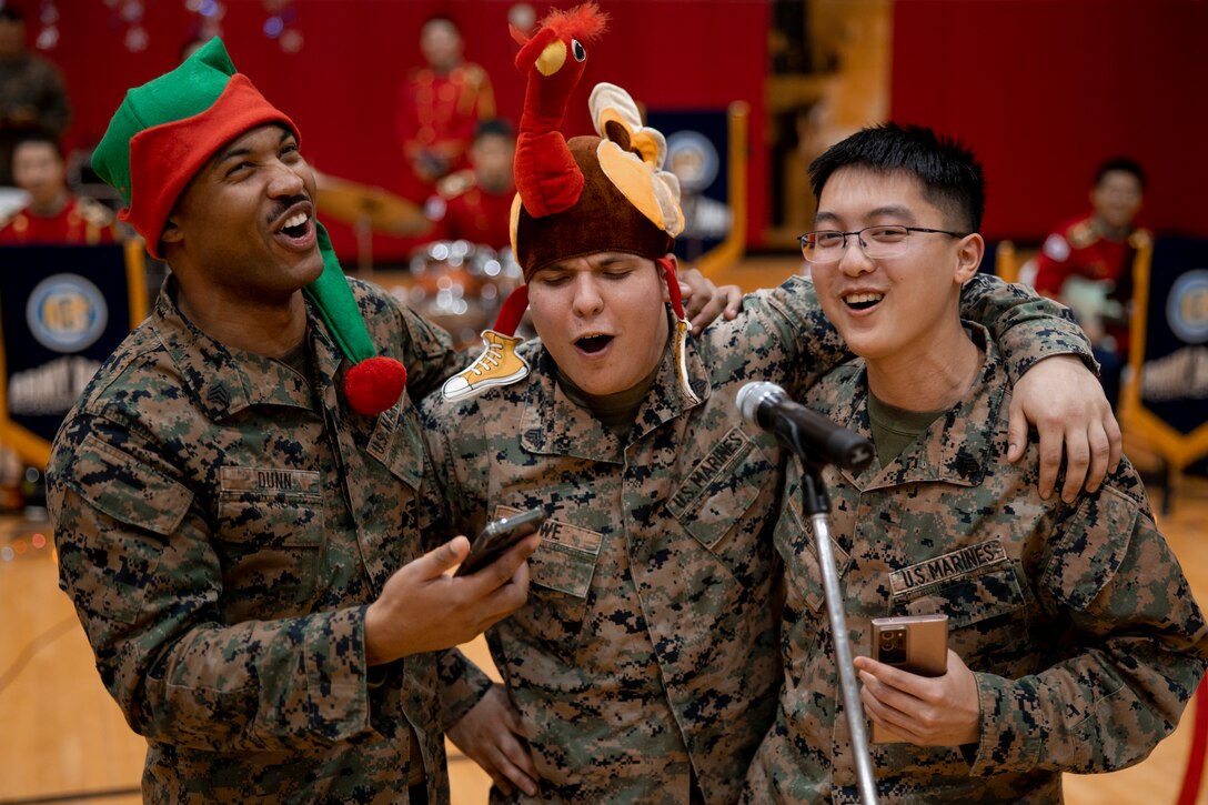 U.S. Marine Corps Sgt. Joshua Dunn, left, a network administrator with Camp Mujuk, Sgt. Austin Howe, center, a data systems administrator with Camp Mujuk, and Sgt. Brandon Nguyen, a financial management resource analyst with Camp Mujuk, compete in a group singing contest during a holiday celebration on Camp Mujuk, Republic of Korea, Dec. 15, 2022. Camp Mujuk invited local Korean children from Sunrin Aeyukwon, Pohang City Dream Start, and Dasom Children’s Center to join them for a holiday celebration. Marines and base personnel organized food and entertainment were organized for the event and the night ended with a tree lighting ceremony. (U.S. Marine Corps photo by Lance Cpl. Thomas Sheng)
