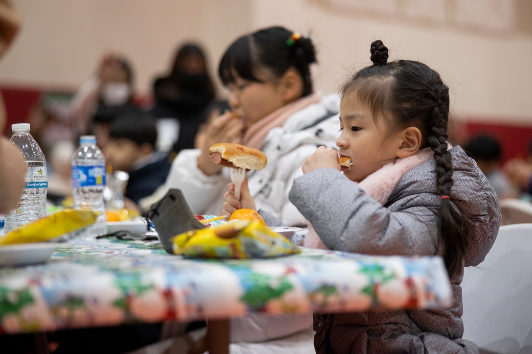A child eats food during a holiday celebration on Camp Mujuk, Republic of Korea, Dec. 15, 2022. Camp Mujuk invited local Korean children from Sunrin Aeyukwon, Pohang City Dream Start, and Dasom Children’s Center to join them for a holiday celebration. Marines and base personnel organized food and entertainment were organized for the event and the night ended with a tree lighting ceremony. (U.S. Marine Corps photo by Lance Cpl. Thomas Sheng)