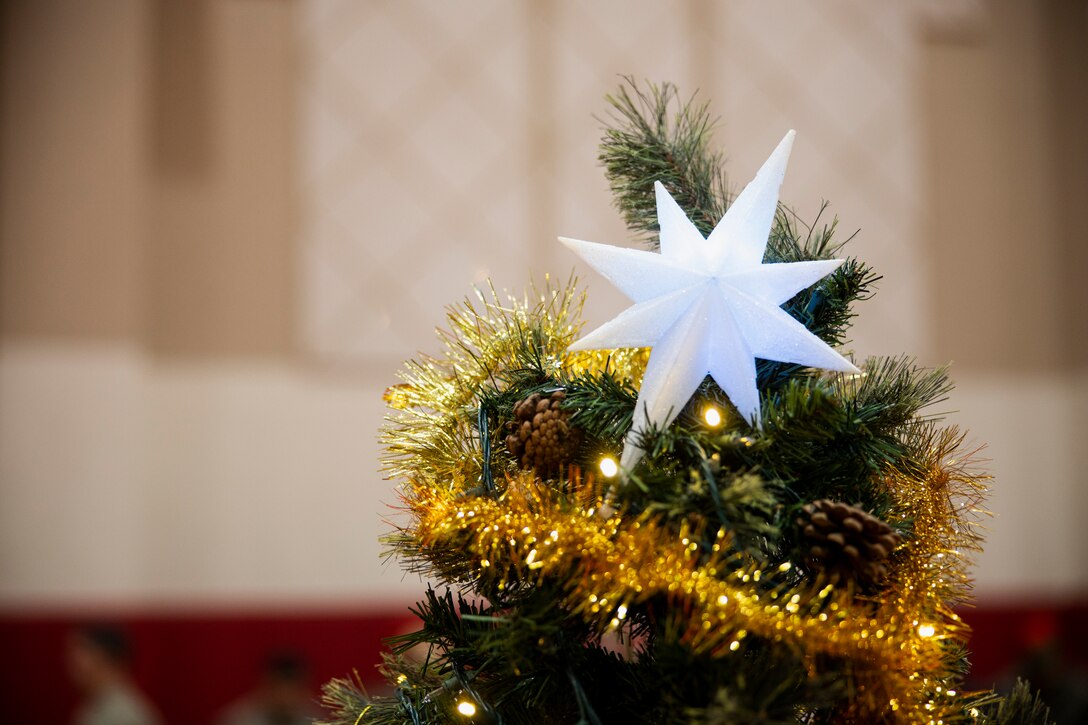 A Christmas star is hung on a tree during a holiday celebration on Camp Mujuk, Republic of Korea, Dec. 15, 2022. Camp Mujuk invited local Korean children from Sunrin Aeyukwon, Pohang City Dream Start, and Dasom Children’s Center to join them for a holiday celebration. Marines and base personnel organized food and entertainment were organized for the event and the night ended with a tree lighting ceremony. (U.S. Marine Corps photo by Lance Cpl. Thomas Sheng)