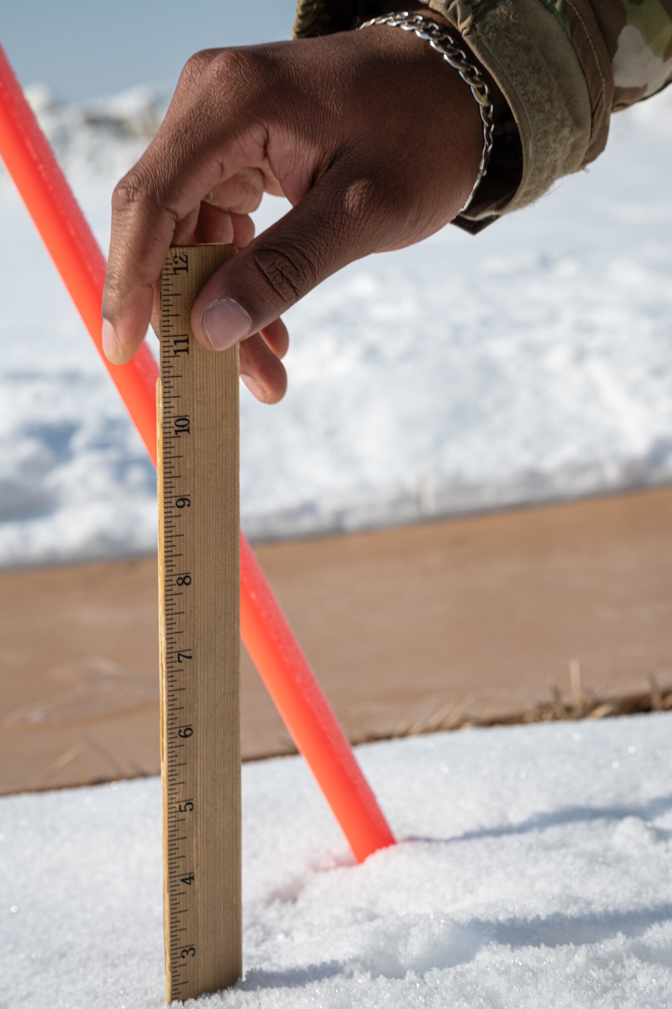 Senior Airman Patrick Bell, 8th Operations Support Squadron weather forecaster, measures snow depth at Kunsan Air Base, Republic of Korea, Dec. 27, 2022. To perform accurate average snow readings on Kunsan’s surface, weather flight personnel must measure various locations accounting for different heights and wind levels around the base. (U.S. Air Force photo by Staff Sgt. Sadie Colbert)