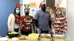 a group of four people stand in front of a prepared meal