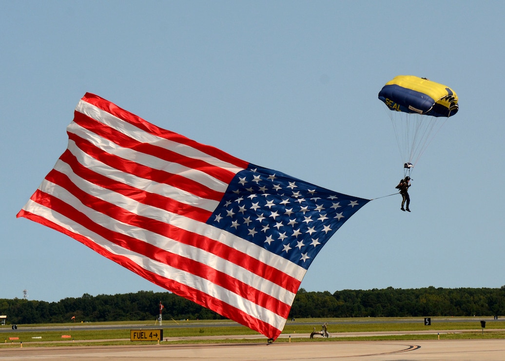A member of the Leap Frog Team jumps with the American flag during the national anthem at the 2022 Naval Air Station (NAS) Oceana Air Show. The NAS Oceana Air Show's theme was "Back to the Beach", as it has been two years since the last performance.