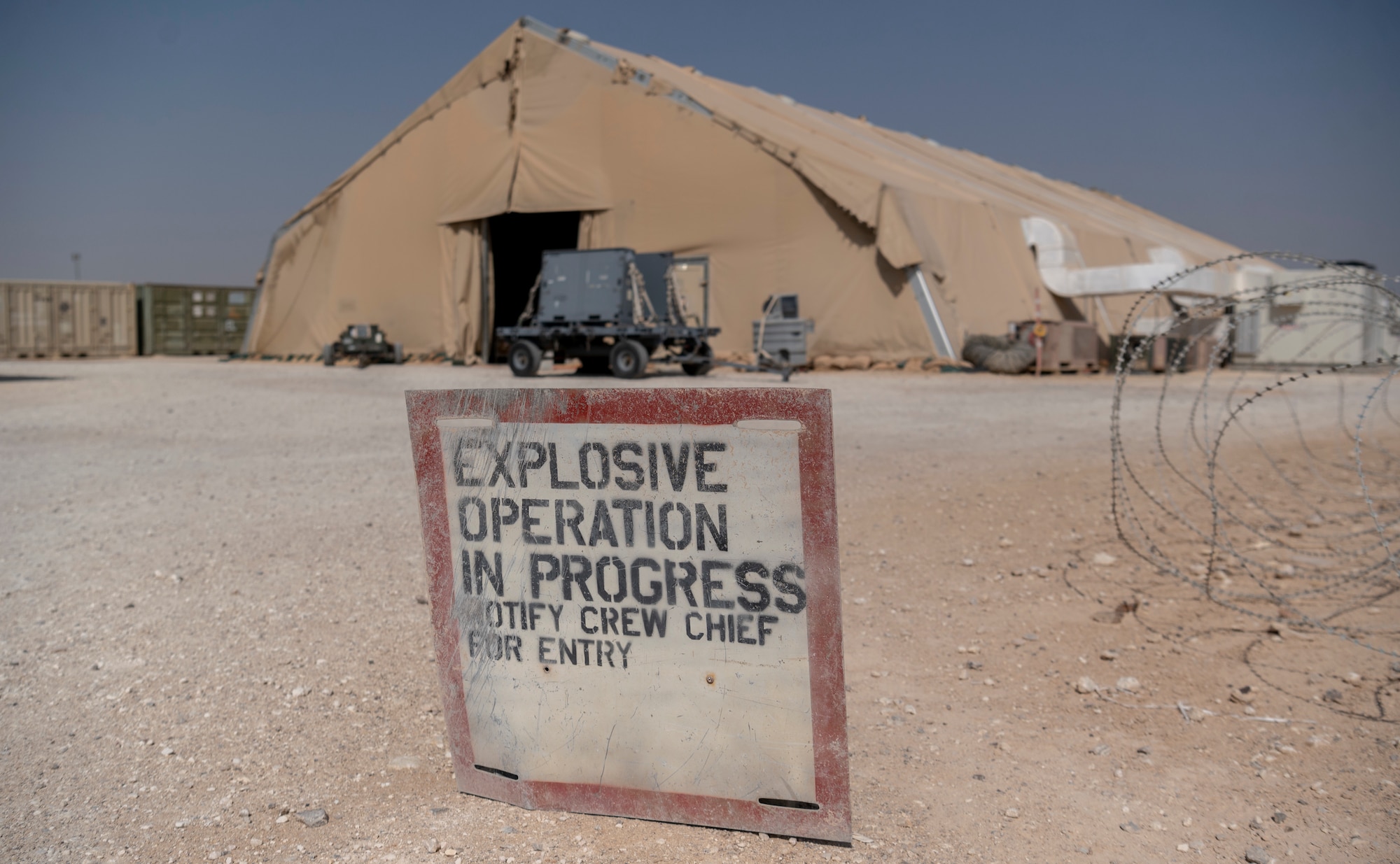 A sign in front of the Munitions facility, 332d Expeditionary Maintenance Squadron, Munitions Flight at an undisclosed location, Southwest Asia, Oct. 28, 2022. The sign warns against unauthorized entry, as the tent contains explosive materials. (U.S. Air Force photo by: Tech. Sgt. Jeffery Foster)