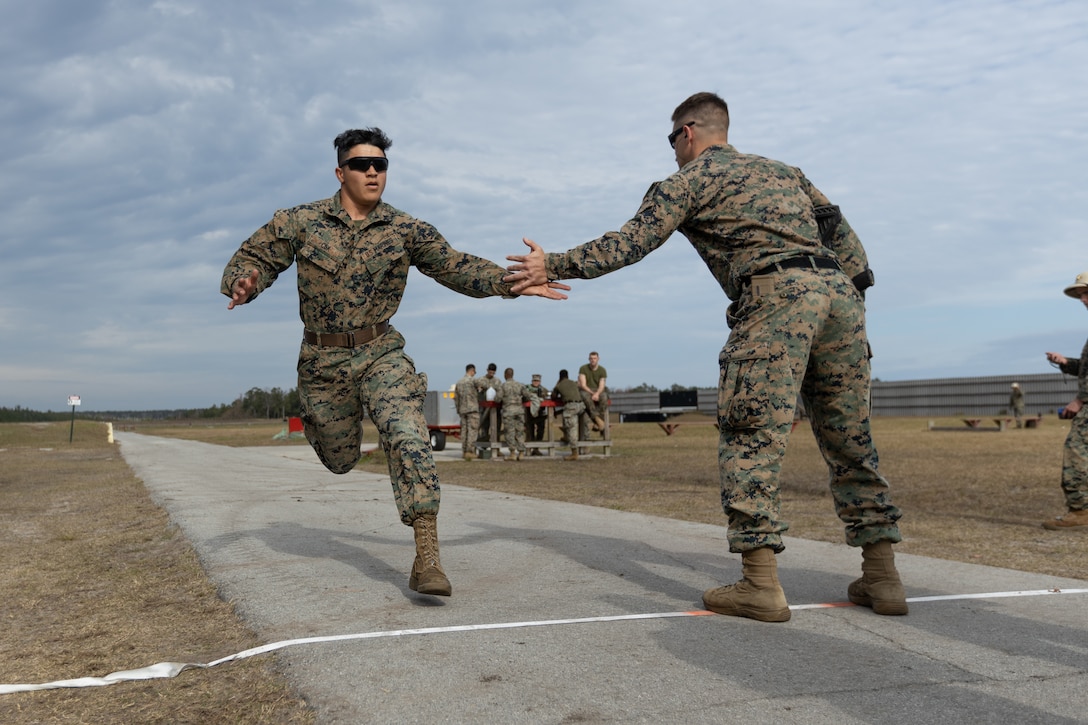 U.S. Marine Corps Cpl. Dylan Cox, left, a maintenance technician, tags in his teammate, 1st Lt. Gregory Johnson, right, a combat engineer officer, both with 2nd Combat Engineer Battalion, during the final stage of the Intramural Marksmanship Competition on Stone Bay, Marine Corps Base Camp Lejeune, North Carolina, Dec. 7, 2022. The Marine Corps Intramural Marksmanship Competition inspires unit cohesion and mission readiness by allowing Marines to compete and improve lethality with both rifle and pistol weapons. (U.S. Marine Corps photo by Cpl. Antonino Mazzamuto)
