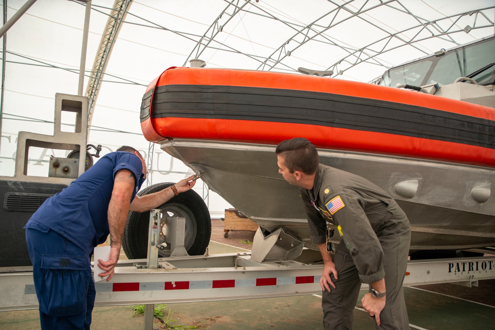 Petty Officer 1st Class Blaine Green (left) and Lt. Cmdr. Christopher Smith (right), inspect a small boat for damages. (U.S. Coast Guard photo)