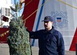 Petty Officer 2nd Class Benjamin Slappey of Coast Guard Cutter Mackinaw (WLBB 30) prepares to present a symbolic Christmas tree at Chicago's Navy Pier during the 23rd annual Christmas Ship ceremony Dec. 3, 2022.