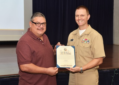 JOINT BASE SAN ANTONIO-FORT SAM HOUSTON – (Dec. 8, 2022) – Alfredo Gonzalez, of El Paso, Texas, a financial management analyst, assigned to Naval Medical Research Unit (NAMRU) San Antonio, was recognized by Commanding Officer Capt. Gerald DeLong as the Fiscal Year 2022 “Support Staff” Civilian of the Half Year (Second Half) during an All Hands meeting held at the Military and Family Readiness Center.  Gonzalez, a retired U.S. Coast Guardsman and graduate of Thomas Edison State College in Trenton, N.J., has served as a Navy civilian for five years. NAMRU San Antonio is one of the leading research and development laboratories for the U.S. Navy under the Department of Defense and is one of eight subordinate research commands in the global network of laboratories operating under the Naval Medical Research Center in Silver Spring, Md.  Its mission is to conduct gap driven combat casualty care, craniofacial, and directed energy research to improve survival, operational readiness, and safety of DOD personnel engaged in routine and expeditionary operations. (U.S. Navy photo by Burrell Parmer, NAMRU San Antonio Public Affairs/Released)