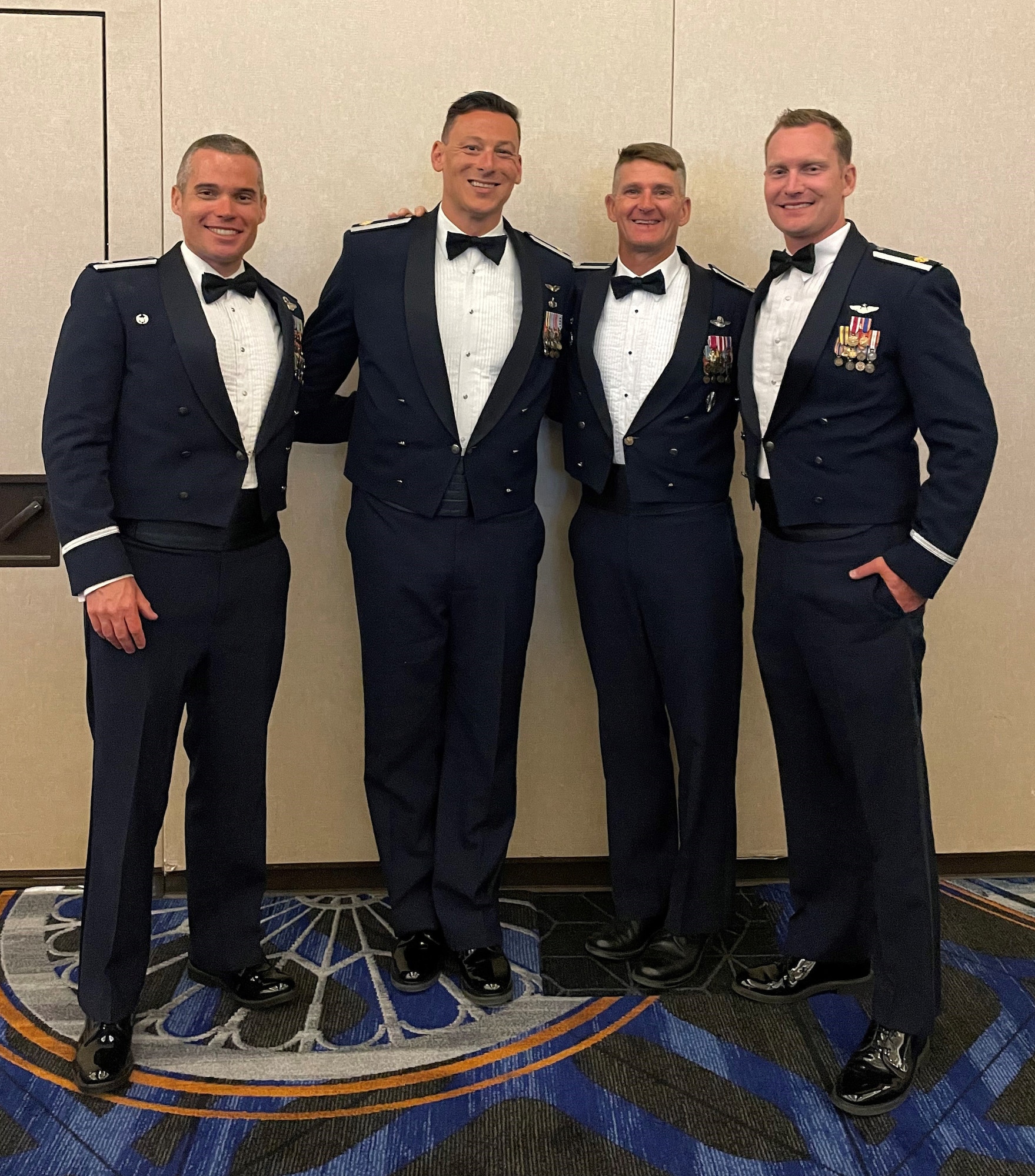 An image of, from left, U.S. Air Force Lt. Col. Michael K. Long 119th Fighter Squadron commander, Maj. Nicholas A. Loglisci, 119 FS chief of weapons and tactics, Col. Derek B. Routt, 177th Fighter Wing commander, and Maj. Eric R. Emerson, 119 FS director of operations, posing for a group photo at a banquet celebrating Loglisci’s graduation from USAF Weapons School on June 11, 2022 at Nellis Air Force Base, Nevada.
