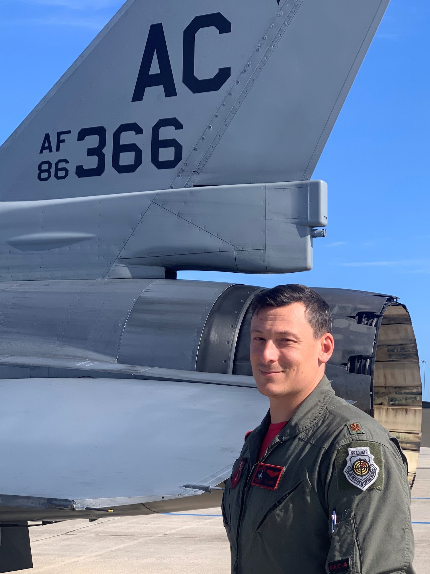 An image of U.S. Air Force Maj. Nicholas A. Loglisci, F-16 fighter pilot and chief of weapons and tactics with the 119th Fighter Squadron, 177th Fighter Wing, New Jersey Air National Guard, posing for a photo wearing his USAF Weapons School Graduate patch, in front of one of the unit's F-16 C Fighting Falcons at the base in Egg Harbor Township, New Jersey, June 10, 2022.