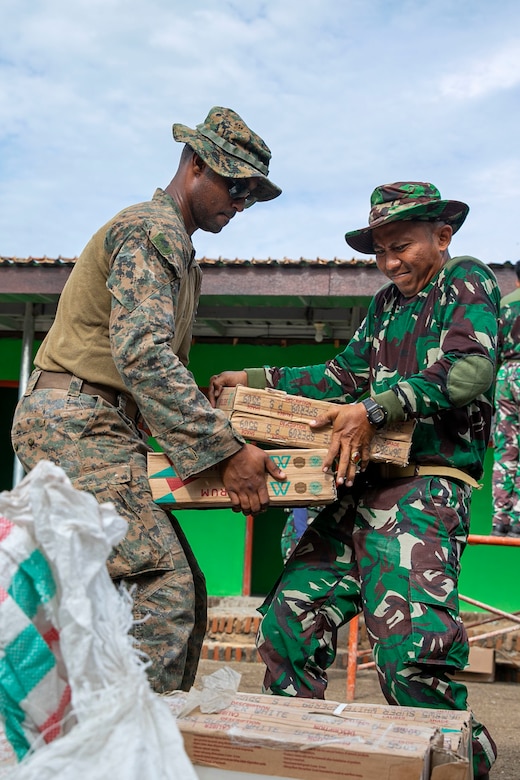 SUMBERWARU, INDONESIA (Dec. 17, 2022) - U.S. Marine Corps Cpl. Ahmed Nur, an electrician with Battalion Landing Team 2/4, 13th Marine Expeditionary Unit, passes boxes of tiles to an Indonesian Korps Marinir (KORMAR) during Cooperation Afloat Readiness and Training/ Marine Exercise (MAREX) Indonesia 2022, Dec. 17. CARAT/MAREX Indonesia is a bilateral exercise between Indonesia and the United States designed to promote regional security cooperation, maintain and strengthen maritime partnerships, and enhance maritime interoperability. In its 28th year, the CARAT series is comprised of multinational exercises, designed to enhance U.S. and partner navies’ and marine corps abilities to operate together in response to traditional and non-traditional maritime security challenges in the Indo-Pacific region. (U.S. Marine Corps photo by Sgt. Brendan Custer)