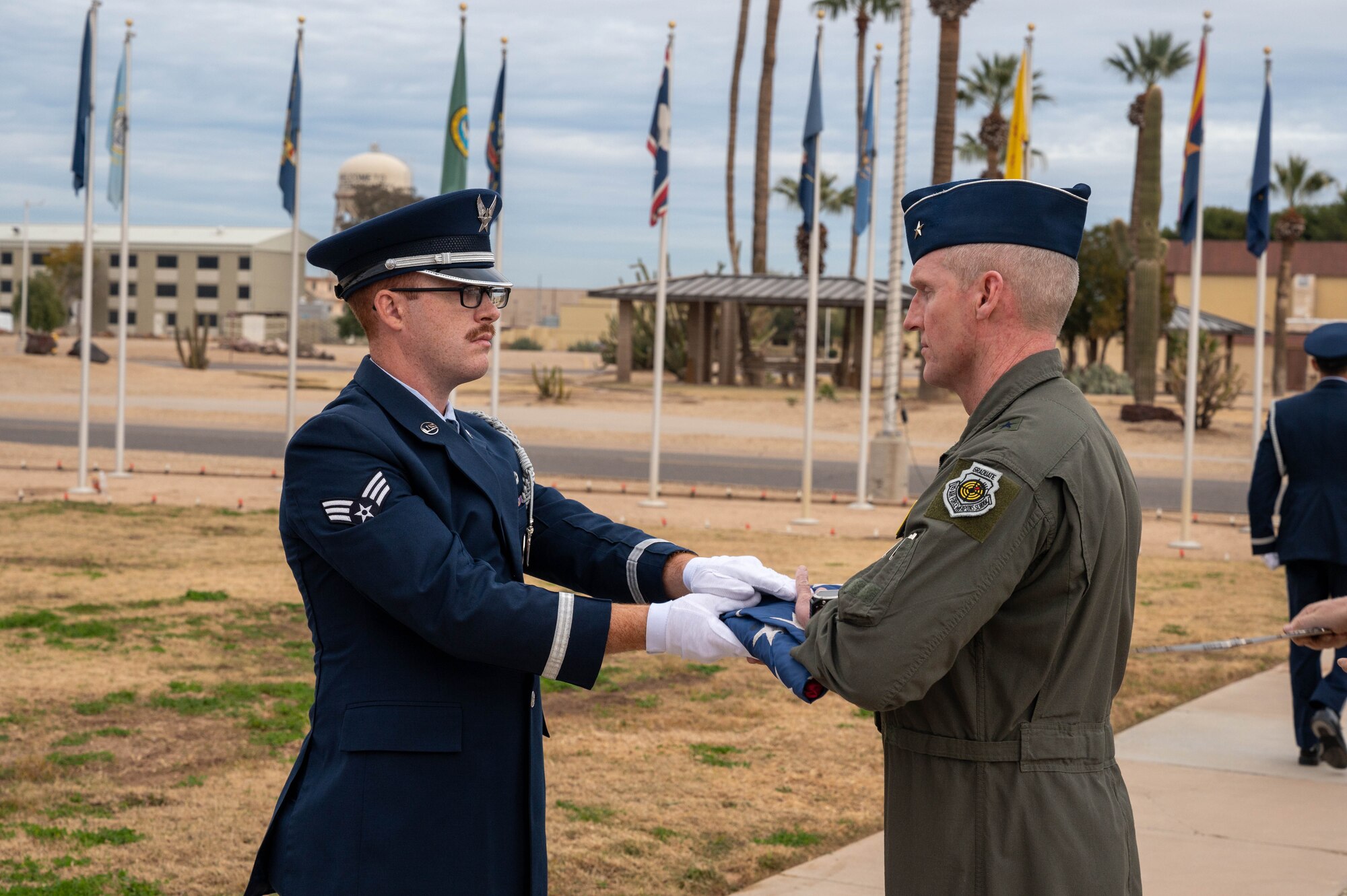 U.S. Air Force Senior Airman Trevor Schmitz, Luke Air Force Base guardsman, presents the U.S. flag to Brig. Gen. Jason Rueschhoff, 56th Fighter Wing commander, during a retreat ceremony, Dec. 27, 2022, at Luke AFB, Arizona.