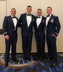 An image of, from left, U.S. Air Force Lt. Col. Michael K. Long 119th Fighter Squadron commander, Maj. Nicholas A. Loglisci, 119 FS chief of weapons and tactics, Col. Derek B. Routt, 177th Fighter Wing commander, and Maj. Eric R. Emerson, 119 FS director of operations, posing for a group photo at a banquet celebrating Loglisci’s graduation from USAF Weapons School on June 11, 2022 at Nellis Air Force Base, Nevada.