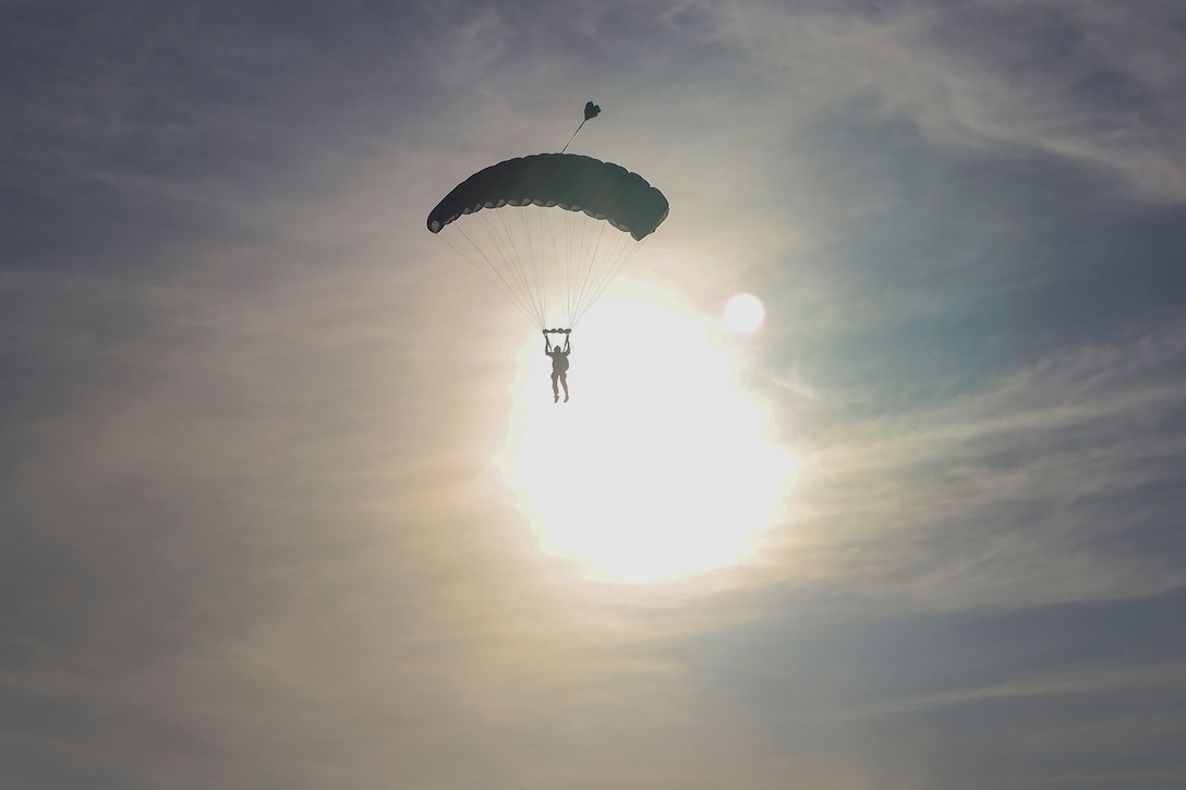 A sunlit Marine parachutes.