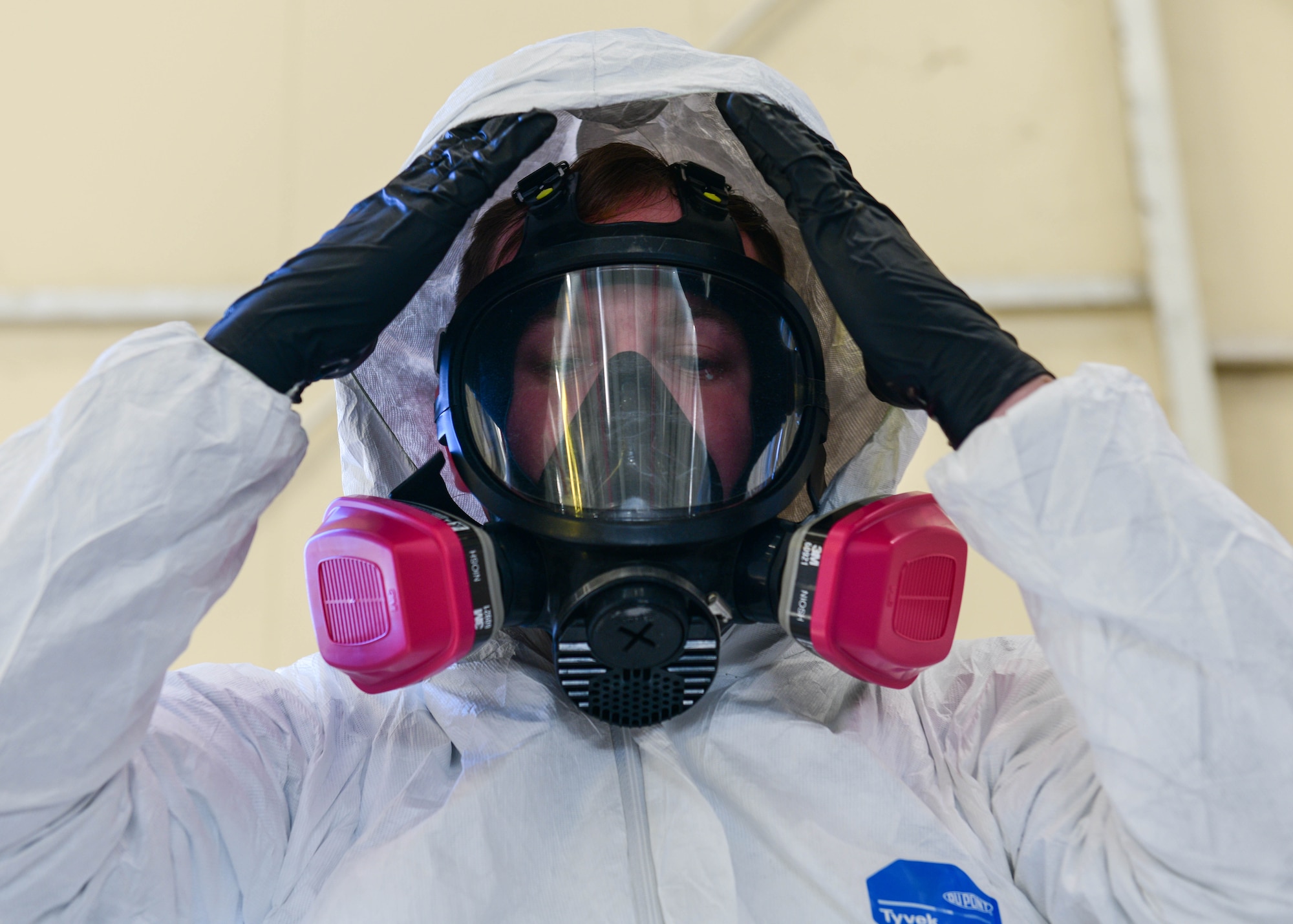 U.S. Staff Sgt. Cameron Keeney, 31st Maintenance Squadron aircraft structural maintenance craftsman, dons his protective equipment at Aviano Air Base, Italy, Dec. 16, 2021. Throughout the entire process of painting the aircraft, ASM personnel wear protective equipment to prevent chemicals from entering their body including respirators, tie backs [white suit worn to protect every inch of skin], gas masks and gloves. (U.S. Air Force photo by Senior Airman Brooke Moeder)