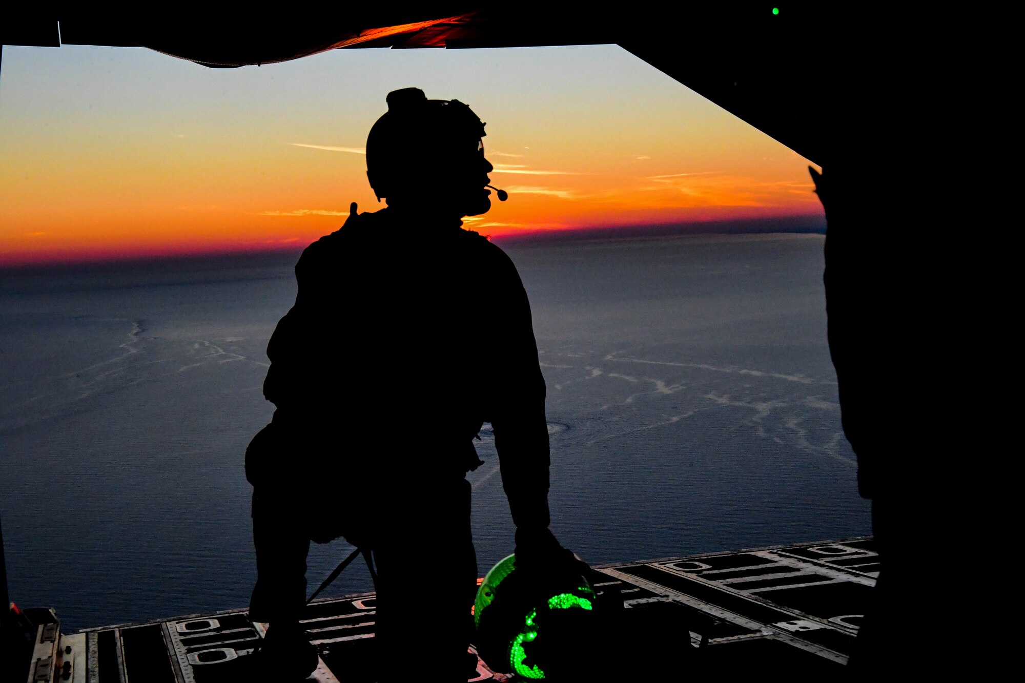 Tech. Sgt. Nathan Young, 57th Rescue Squadron jump master, prepares to drop a search and rescue night light devicel at Aviano Air Base, Italy, Jan. 13, 2021. The ball is used during night operations creating a point for the members jumping to easily see with their night vision goggles. (U.S. Air Force photo by Senior Airman Noah Sudolcan)