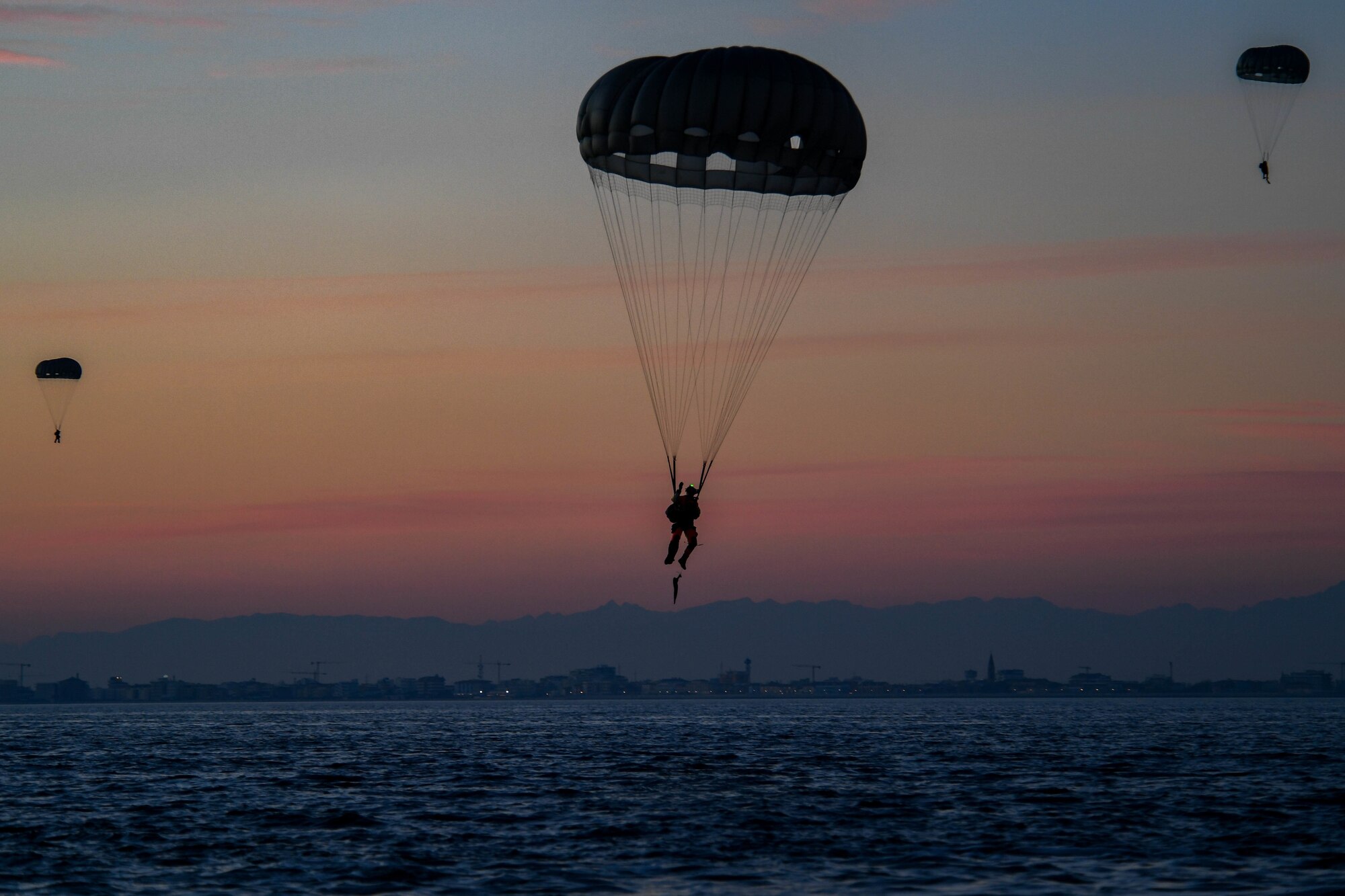 Pararescuemen assigned to the 57th Rescue Squadron drop into the Adriatic Sea near Aviano Air Base, Italy, Jan. 13, 2021.The 57th RQS performs different jumps over a variety of terrains depending on the scenario. This exercise included free fall and static jumps over land and water. (U.S. Air Force photo by Senior Airman Brooke Moeder)