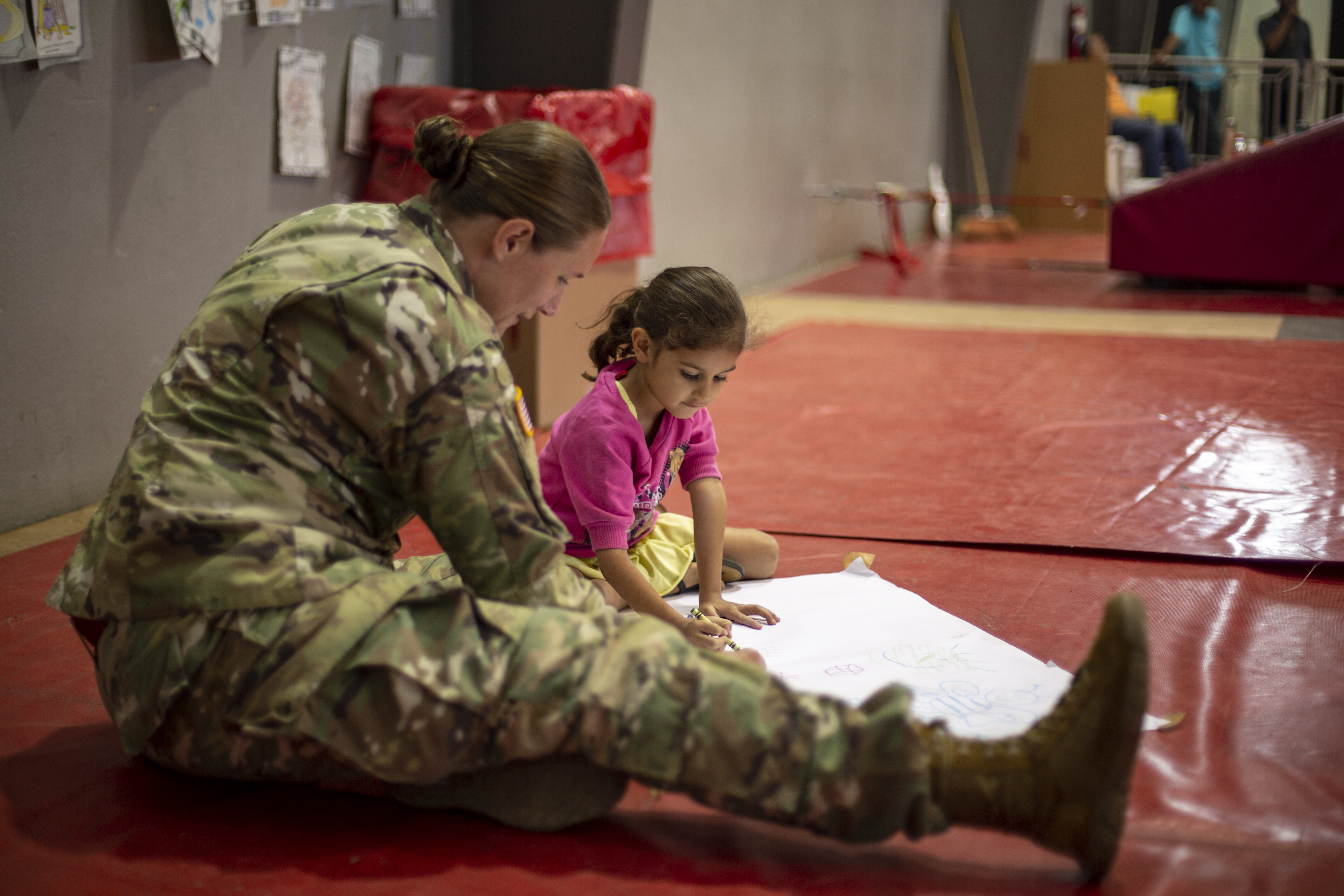A Marine talking with a child sitting on the floot.