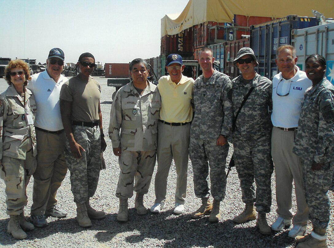 Civilian and military deployers pose in a yard with some famous sports personalities.