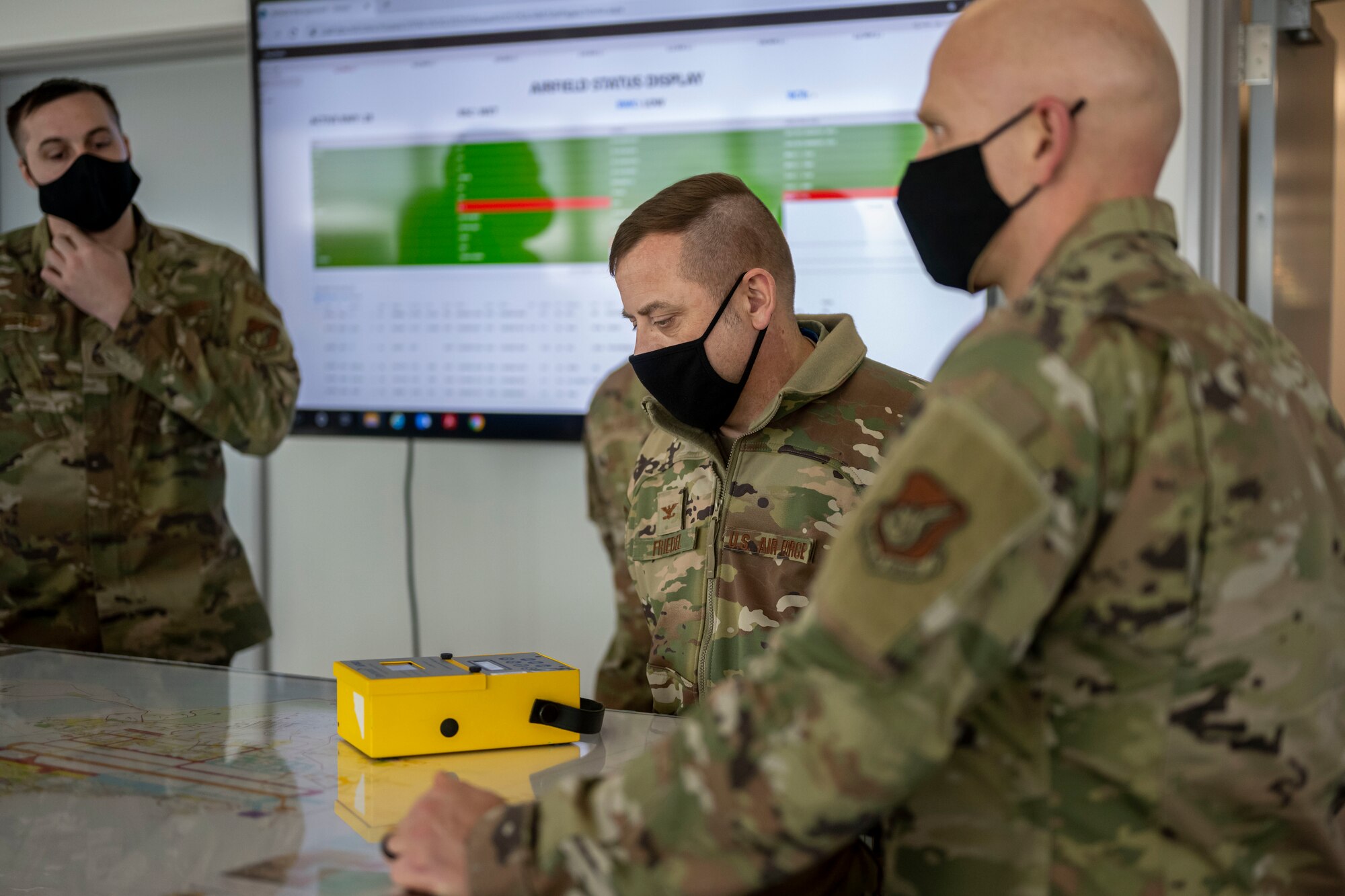 Male service member looking at a yellow electronic box used to determine how much friction a road has.