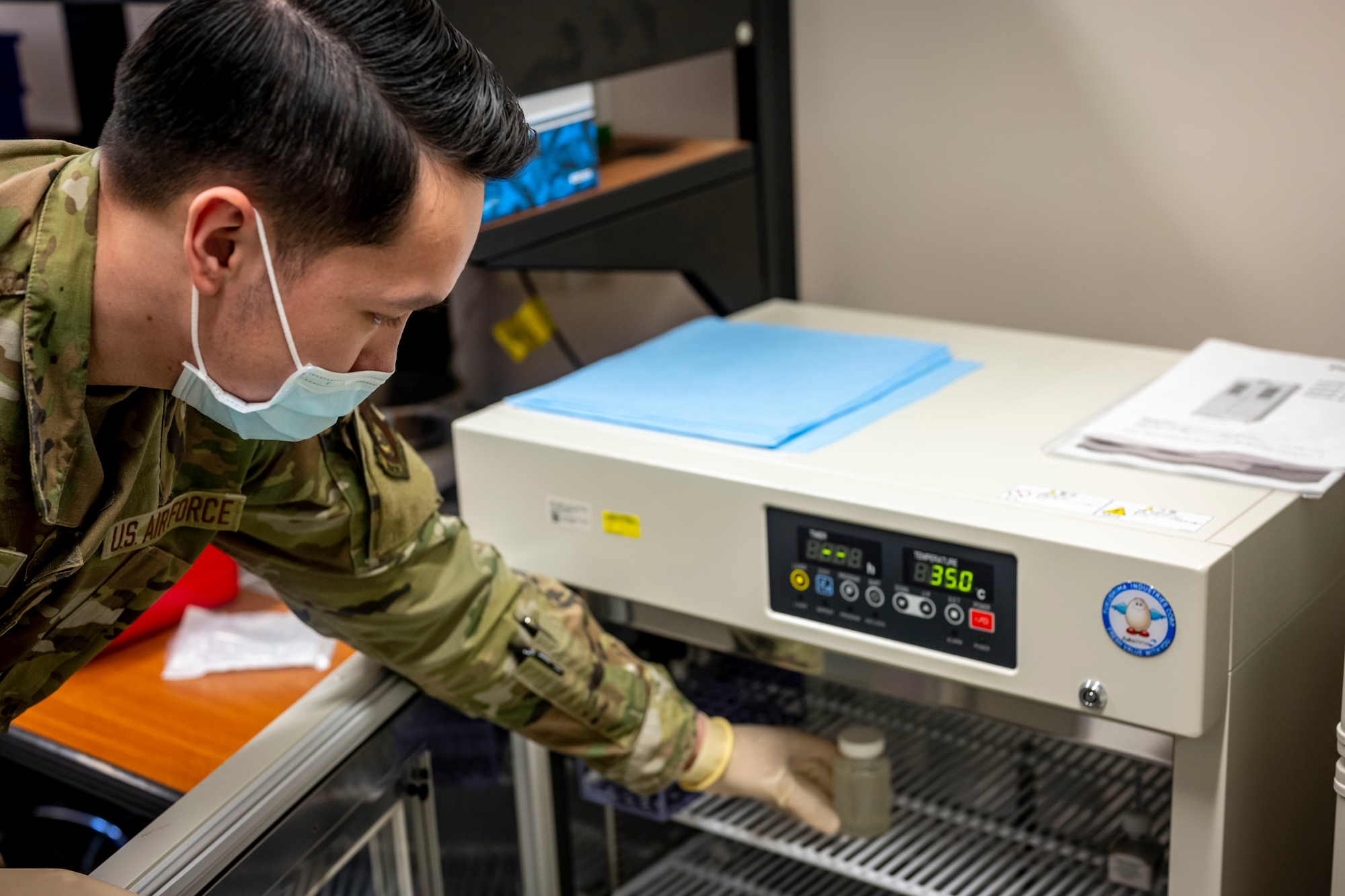 Airman placing bottle into an incubator.