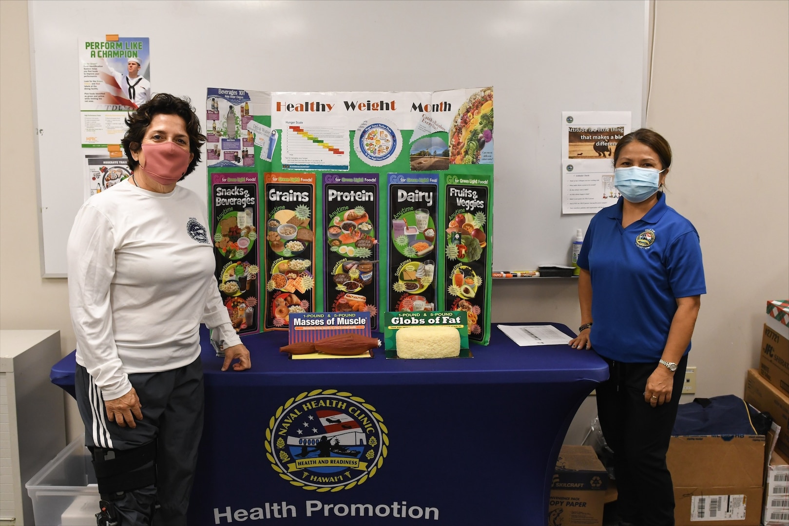 Two health promotions instructors stand at the table showing weight management resources.