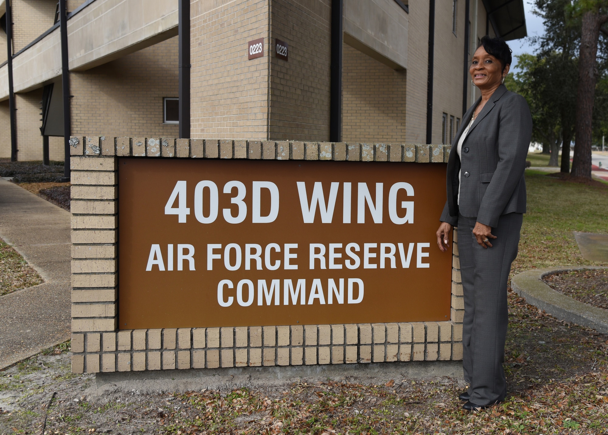 Mrs. Patricia Jackson standing next to the 403rd Wing, Air Force Reserve Command sign outside of the headquarters building.