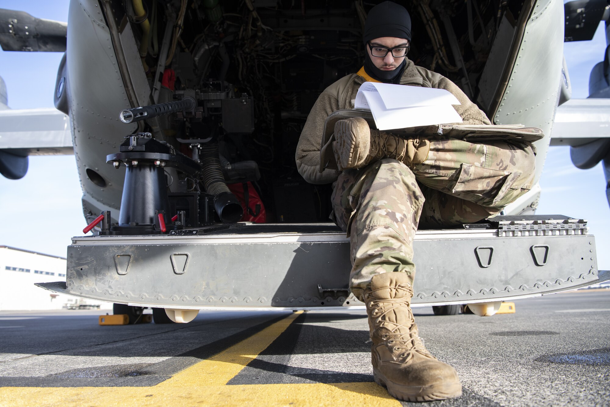 A maintenance Airman sits on the loading deck of a CV-22