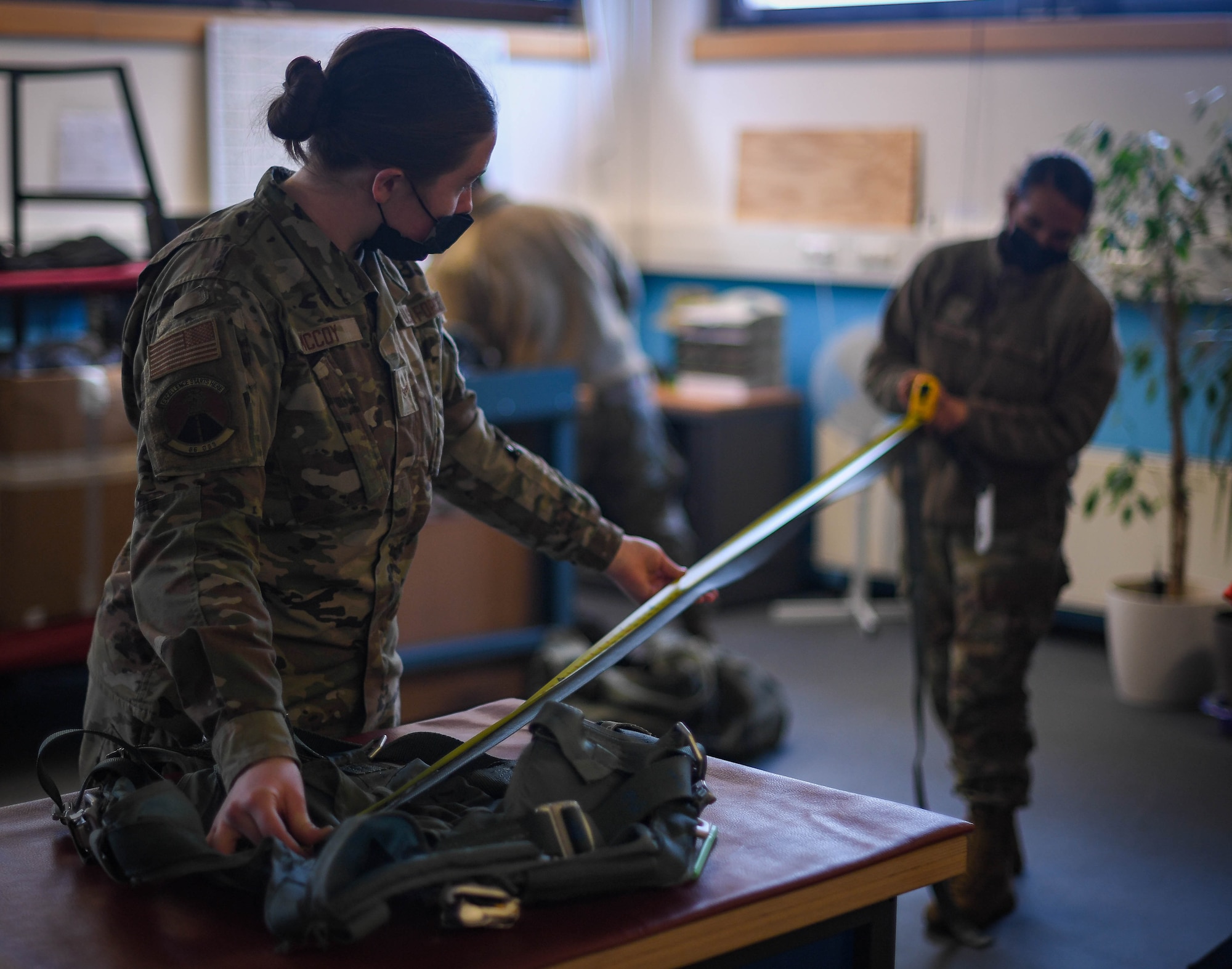 U.S. Air Force Airman 1st Class Emily McCoy, 86th Operations Support Squadron aircrew flight equipment flight line technician, left, and Senior Airman Alicia Wallace, 86 OSS aircrew flight equipment chemical section lead, measure the length of a strap for a harness at Ramstein Air Base, Germany, Jan. 20, 2022. Aircrew flight equipment Airmen ensure that all flight and safety equipment is in proper working order prior to flights. (U.S. Air Force photo by Airman 1st Class Jared Lovett)