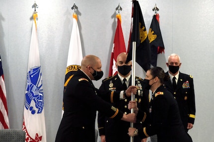 Lt. Col. Colleen Shepherd, right, commander of Headquarters Battalion, Army National Guard, hands the guidon of Headquarters and Headquarters Company, Army Guard to Maj. Matt Jordan, company commander, during an activation ceremony of both the company and the battalion at the Herbert R. Temple Army National Guard Readiness Center, Arlington Hall Station in Arlington Virginia, Jan. 28, 2022. The activation of the company and battalion brings administrative and related battalion-level responsibilities for the Army Guard directorate within the NGB, where previously those items fell to the Military District of Washington. The MDW now serves as the brigade-level headquarters for those actions.