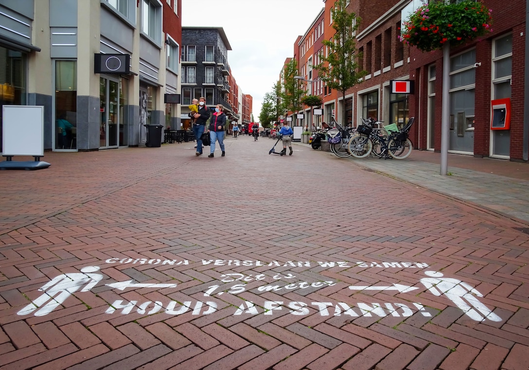WADDINXVEEN, THE NETHERLANDS: Shopping in Dutch city center during virus outbreak. People wearing surgical face
mask for protection. Chalk text in Dutch means ‘We beat Corona together, this is 1.5 m ‘ )Image by Kiwik at Shutterstock.
ID: 1812478942)
