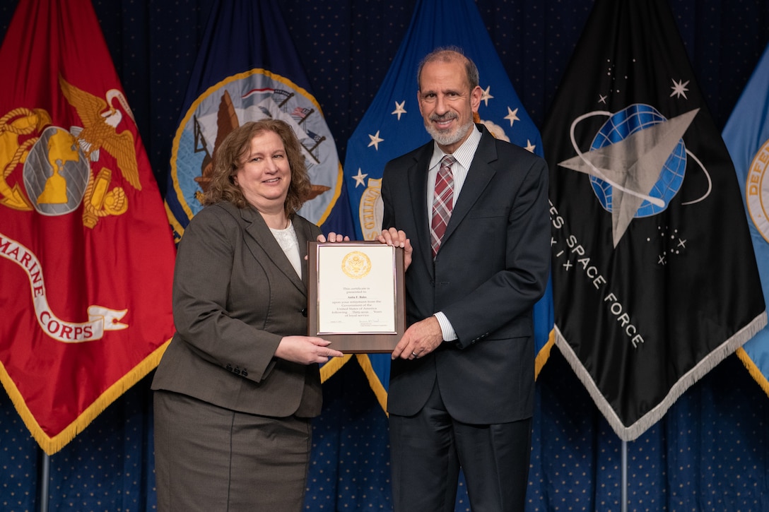 man and women pose with retirement certificate