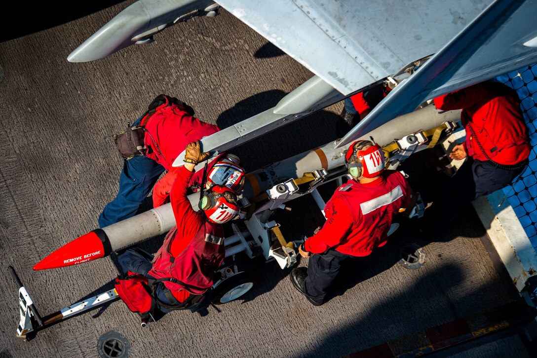 Sailors load ordnance on a military ship.