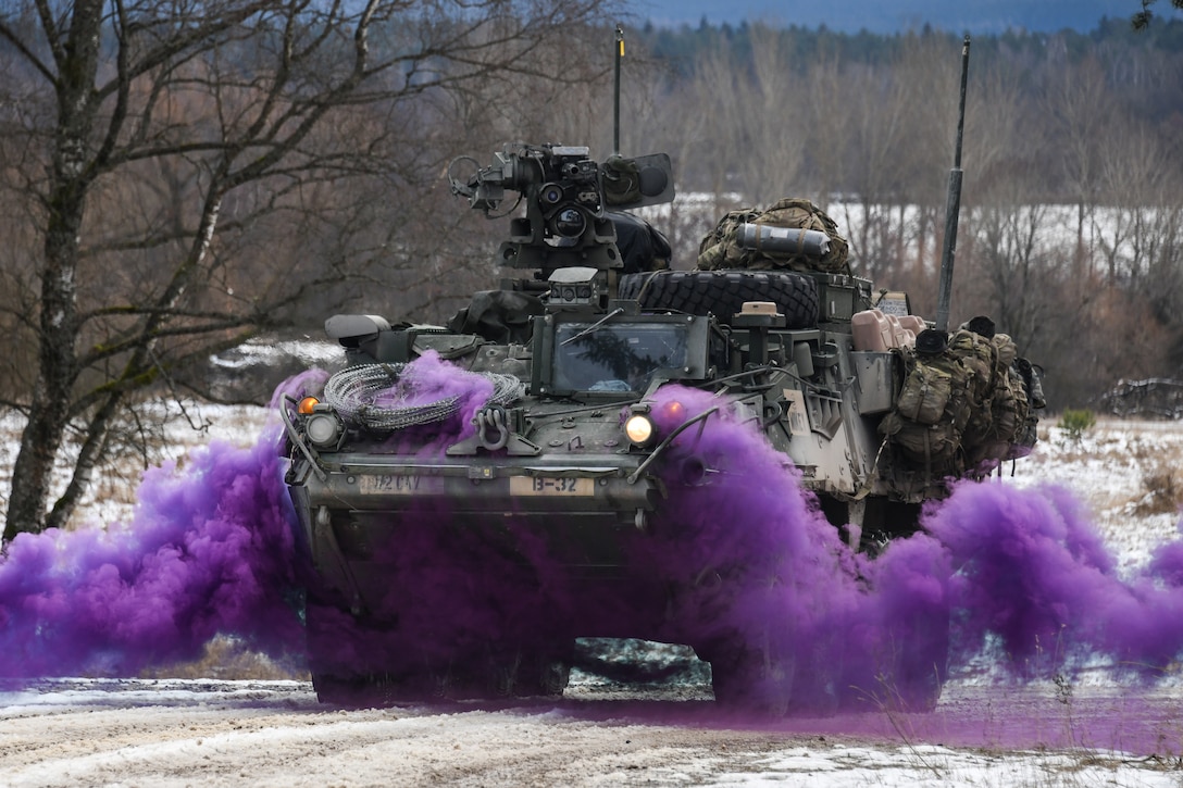 Purple smoke billows from underneath a Stryker vehicle.