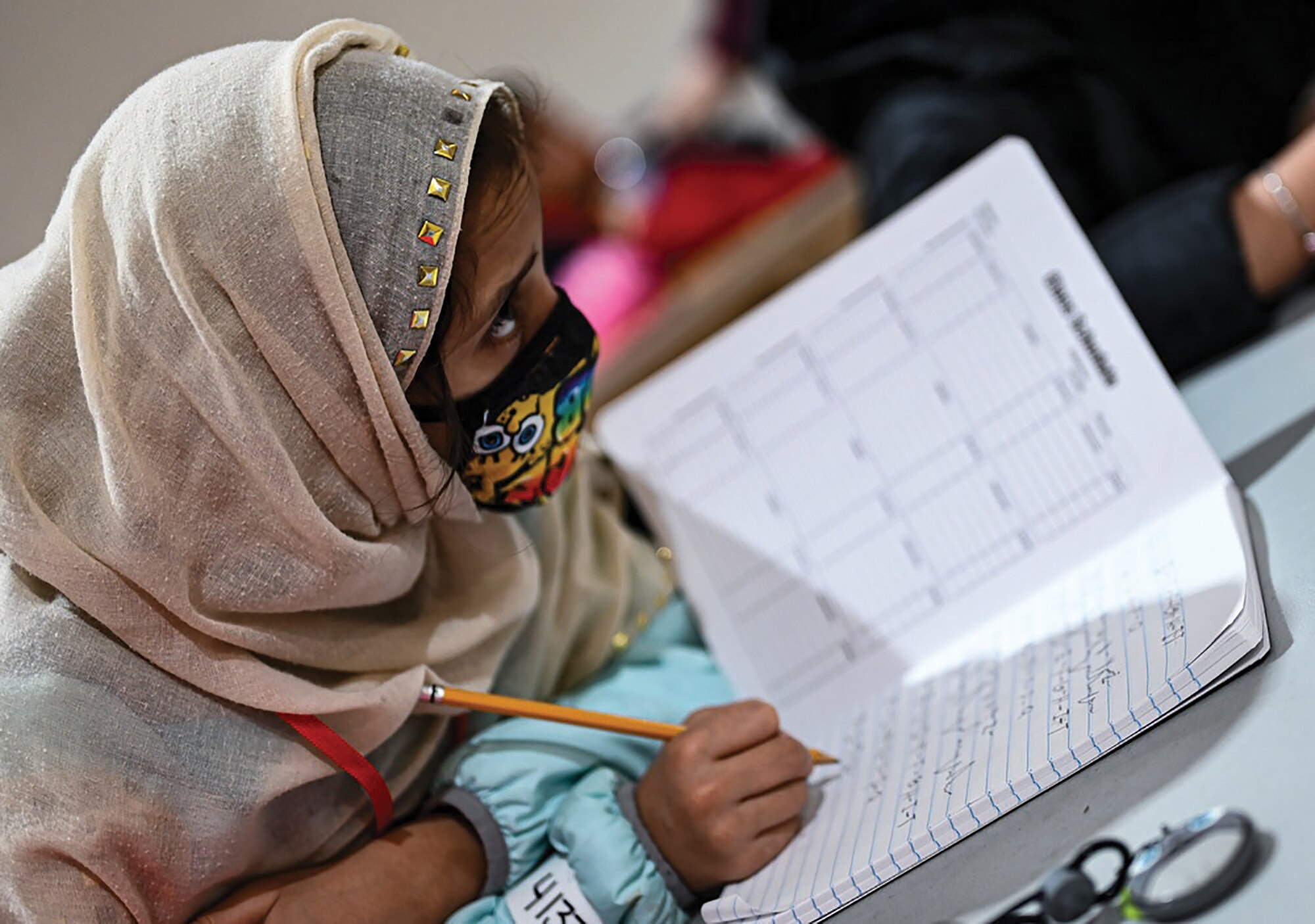 An Afghan student writes out her ABCs during community-based education in Liberty Village, Joint Base McGuire-Dix-Lakehurst, New Jersey, Dec. 20, 2021.