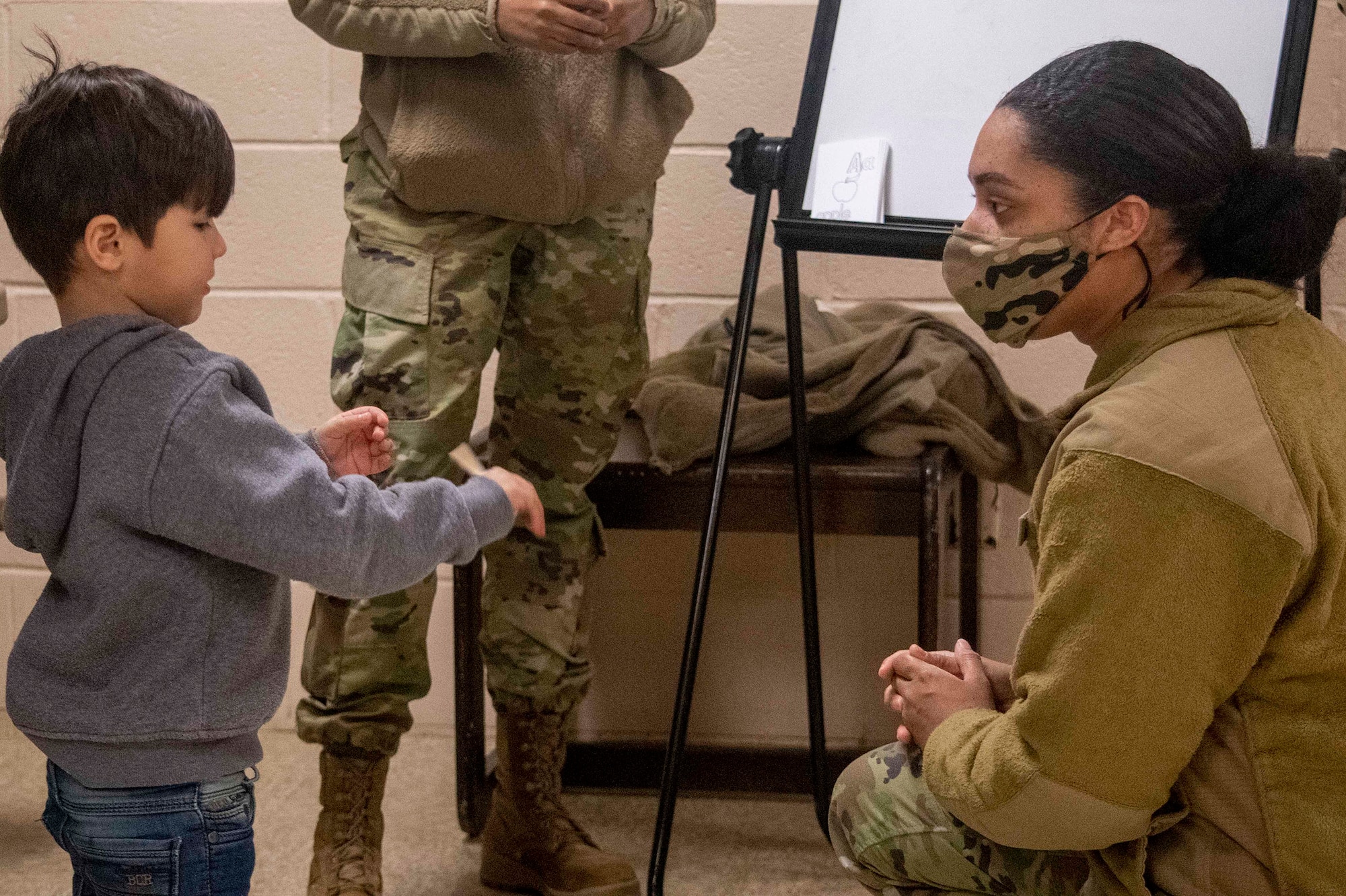 U.S. Air Force Senior Airman Taylor McAfee, Task Force-Liberty Joint Readiness Center non-medical escort, teaches English phrases to Afghan children in Liberty Village on Joint Base McGuire-Dix-Lakehurst, New Jersey, Feb. 1, 2022. The Department of Defense, through U.S. Northern Command, and in support of the Department of Homeland Security, is providing transportation, temporary housing, medical screening, and general support for at least 11,000 Afghan evacuees at Liberty Village, in permanent or temporary structures, as quickly as possible. This initiative provides Afghan personnel essential support at secure locations outside Afghanistan