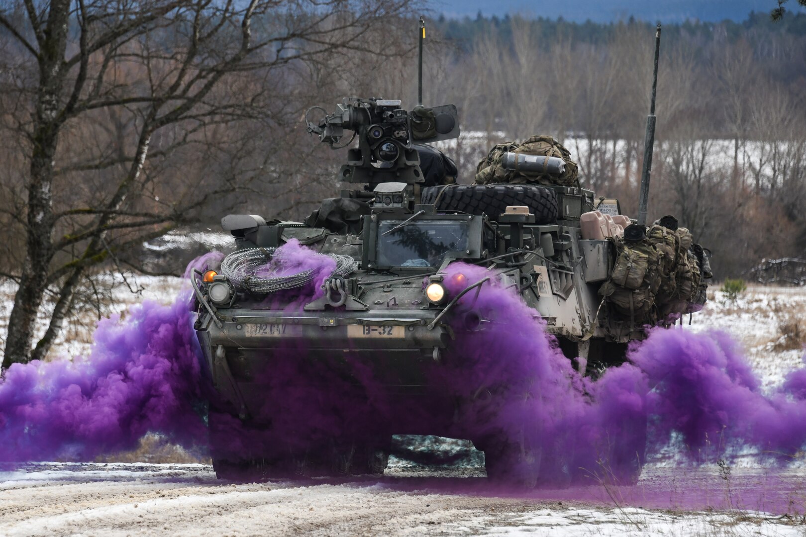 Purple smoke billows from underneath a Stryker vehicle.