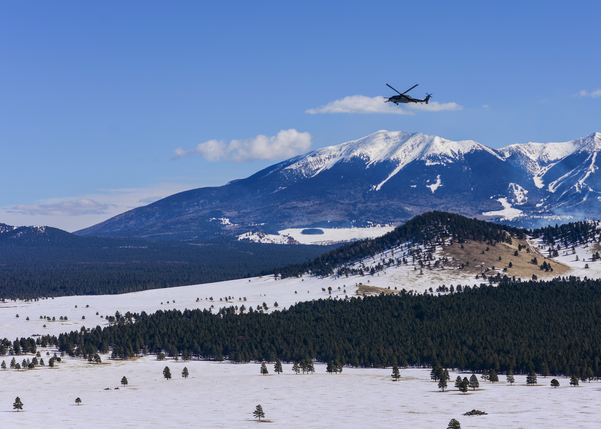 a photo of a helicopter flying over the mountains