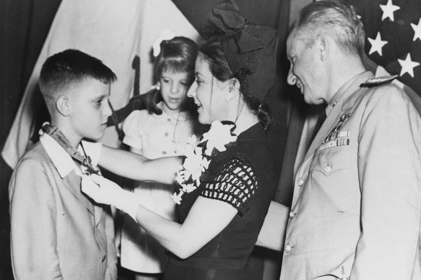 A woman places a medal around a boy's neck. A girl and another man watch.