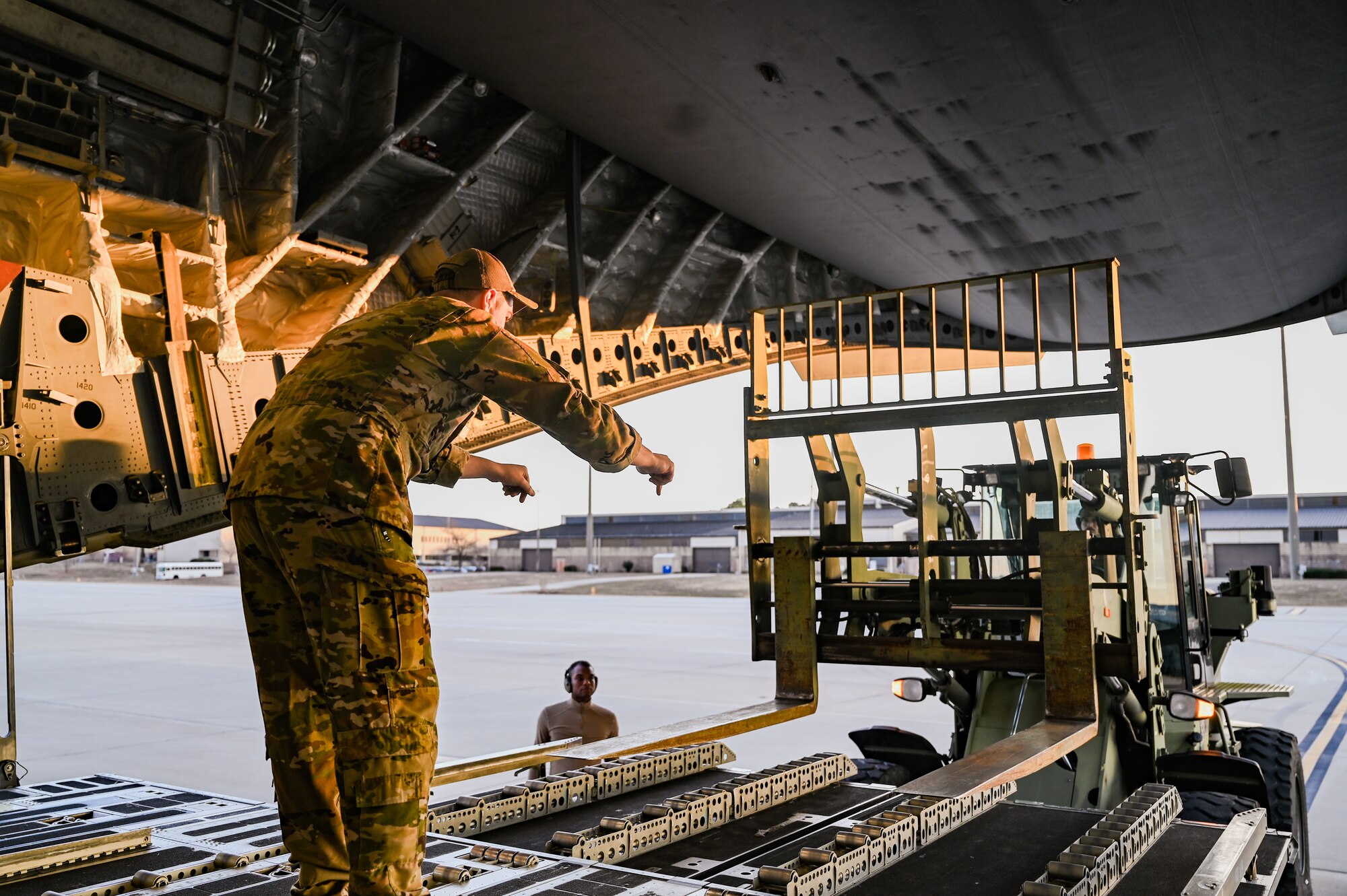 Airmen positions forklift behind a C-17 Globemaster III.