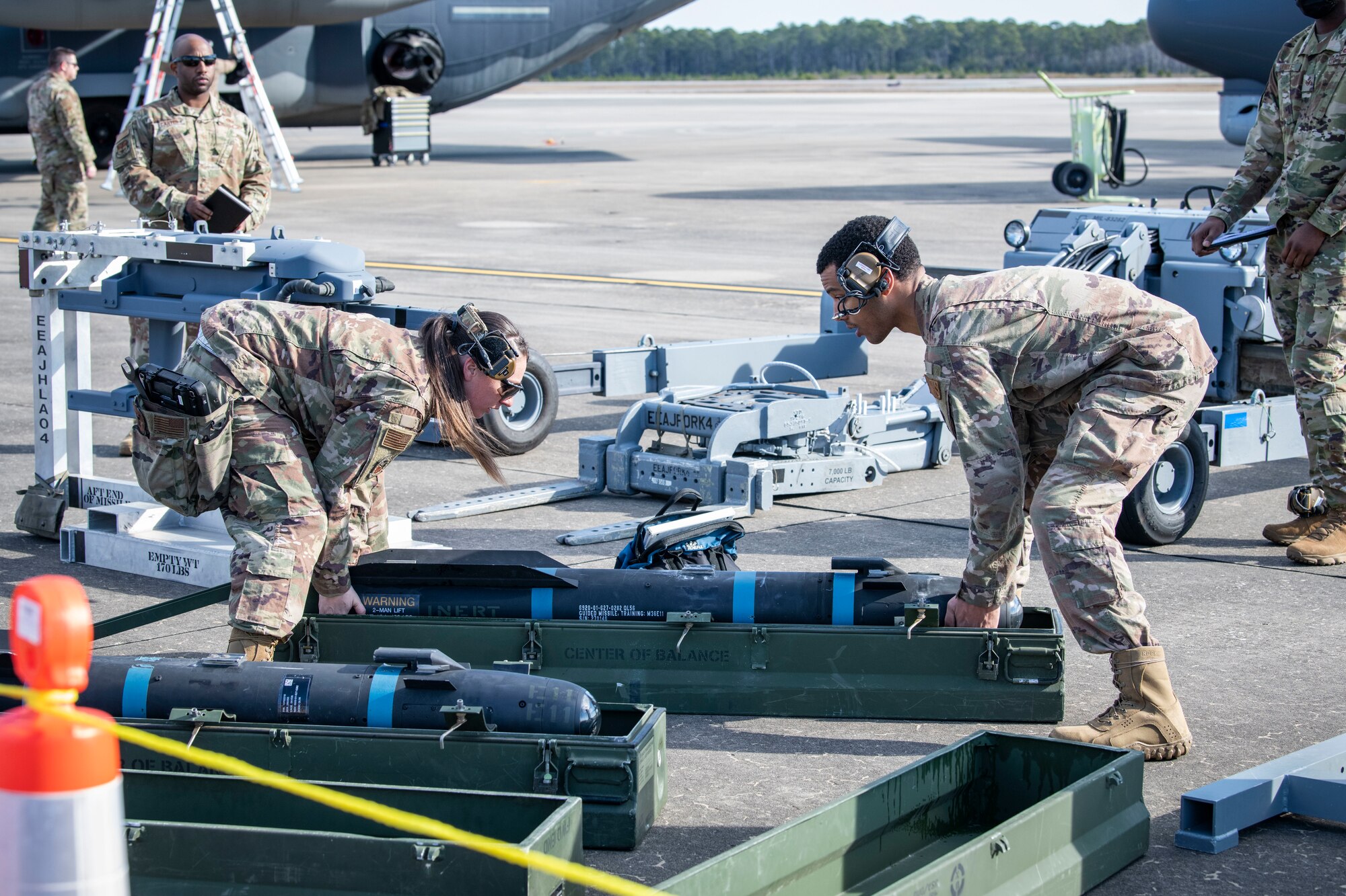 U.S. Air Force Staff Sgt. Jillian Martin, left, a 73rd Aircraft Maintenance Unit weapons load crew chief, and U.S. Air Force Senior Airman Adrian Bethea, right, a 73rd AMU load crew member, lift an AGM-114 Hellfire missile together during the 2022 Weapons Load Crew of the Year Competition, Jan. 31, 2022, at Hurlburt Field, Florida.