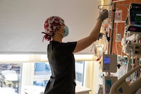 A soldier wearing a face mask and gloves removes a blood bag during COVID-19 response operations.