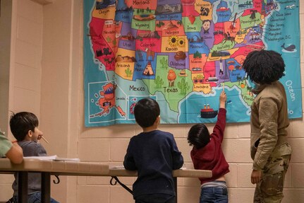 Senior Airman Cicely McWhorter, 87th Aerial Port Squadron passenger services apprentice, currently assigned as Task Force-Liberty Joint Readiness Center floor operations, teaches Afghan children the names of the 50 states in Liberty Village on Joint Base McGuire-Dix-Lakehurst, New Jersey, Feb. 1, 2022. The Department of Defense, through U.S. Northern Command, and in support of the Department of Homeland Security, is providing transportation, temporary housing, medical screening, and general support for at least 11,000 Afghan evacuees at Liberty Village, in permanent or temporary structures, as quickly as possible. This initiative provides Afghan personnel essential support at secure locations outside Afghanistan.